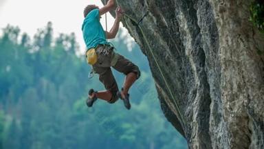 一个<strong>攀岩</strong>者挂在岩石上的特写镜头。垂直岩石。极限运动